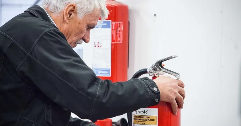 Presto-tekniker kontrollerer ventilen på en brandslukker